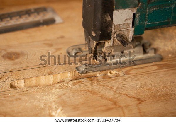 Wood processing. Person cutting wooden board with\
electric jigsaw.