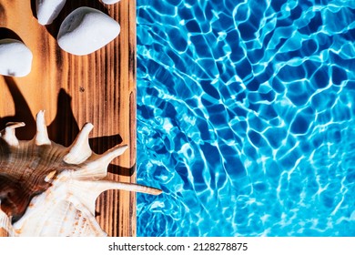 Wood Sand Board, Hot White Salt Stones And Natural Seashell, Conch. Blue Transparent Reflect Wave Water Surface Ocean. Hot Warm Stone Massage Therapy Treatment Concept. Flat Lay. Right Place For Text.