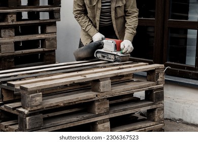 Wood sanding process by using handheld electric belt sander. machine grinding sanding wooden board surface on workbench. - Powered by Shutterstock