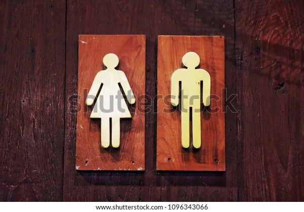 Wood signboard in front of the toilet. Divide\
between men and women.