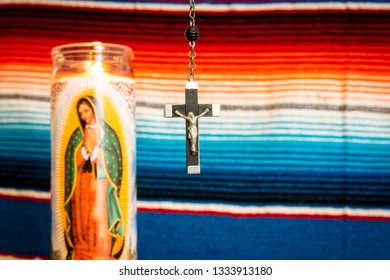 Wood And Silver Crucifix With Virgin Mary Prayer Candle To The Left, With Mexican Blanket As Backdrop. Cathoilc, Easter, Religion Concepts.