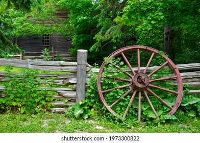 Wood spoke wagon wheel left on the wooden fence on a farmhouse