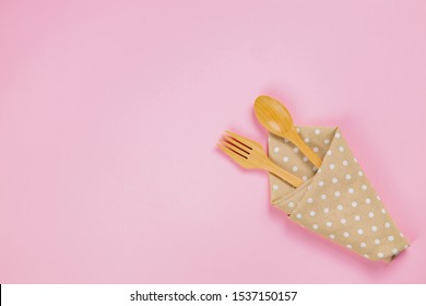 Wood Spoon, Fork And Polka Dot Cloth Napkin On Pink Background