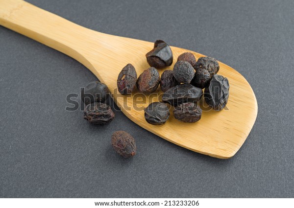 A wood spoon with saw palmetto berries on a
dark background.