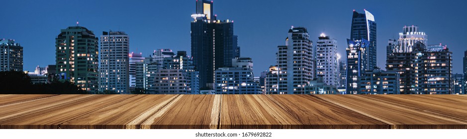 Wood Table With Blurred Background Of Cityscape At Night Lights Scene Urban View,web Banner Header Panoramic,copy Space,empty Space,montage For Show Product For Advertising And Using For Business