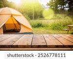 Wood table and Blurred camping and tents in forest.