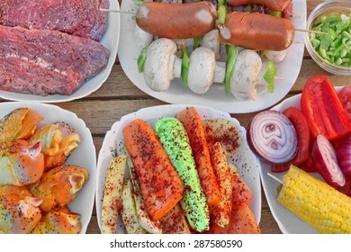 Wood Table With Different Cookout Food For Summer BBQ Grill Family Picnic Party. Beef Steaks, Mushrooms, Corn Cob, Onion, Sausages, Chicken Legs, Bell Pepper, Carrot, Potato, Kebabs, Zucchini