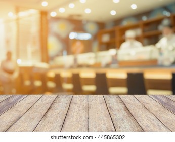 wood table with japanese restaurant and sushi bar interior with chef and customers blur background