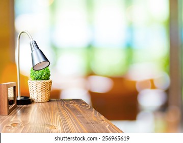 Wood Table With Lamp And Picture Frame At Blurred Garden Cafe Background