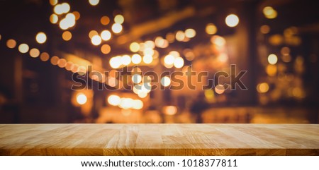 Wood table top (Bar) with blur light bokeh in dark night cafe,restaurant background .Lifestyle and celebration concepts ideas