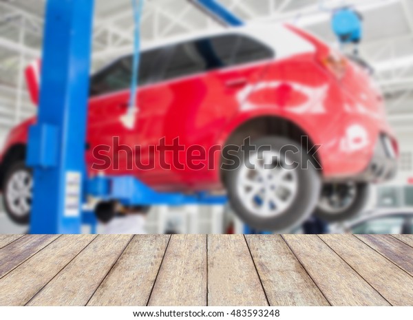 Wood table top with blur car service\
centre background, for montage product\
display