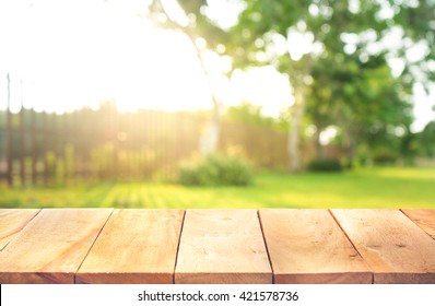 Wood table top with fence and grass in garden background.For  create product display or design key visual layout