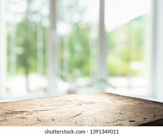 Wood table top on blur of window glass and abstract green from garden with city view in the morning background. For montage product display