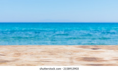 Wood table top on blur summer blue sea. Empty wooden table on the seashore and blue sky. Concept of a summer vacation at sea