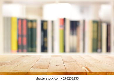 Wood table top on blur bookshelf background - can be used for display or montage your products