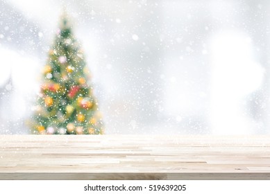 Wood Table Top On Blur Christmas Tree And White Bokeh In Snowfall Background