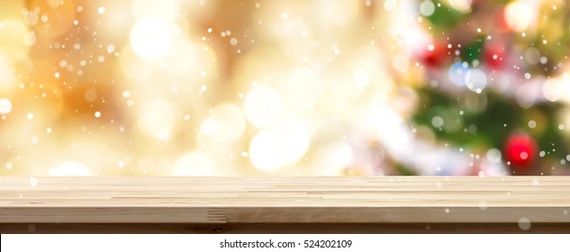 Wood Table Top On  Blur Colorful Christmas Tree And Gold Bokeh Background With Snowfall