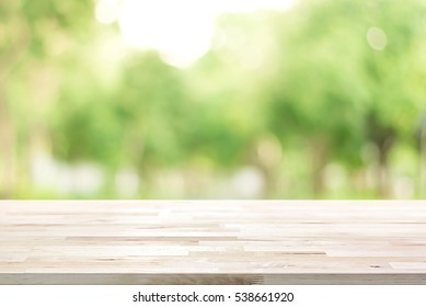 Деревянная столешница на размытом зеленом фоне деревьев в парке - может быть использована для демонстрации или монтажа ваших продуктов