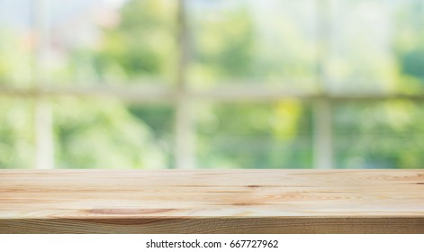 Wood Table Top On Blur Of Window Glass And Abstract Green From Garden Background.