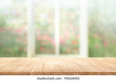 Wood table top on blur of window with garden flower background in morning.For montage product display or design key visual layout
