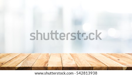 Wood table top on blur glass window wall building background.For montage product display or design key visual layout background.