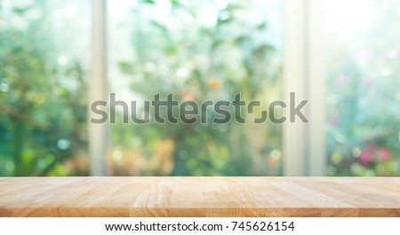 Wood table top on blur of window with garden flower background in morning.For montage product display or design key visual layout