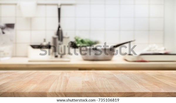 Wood table top on\
blur kitchen room background .For montage product display or design\
key visual layout.
