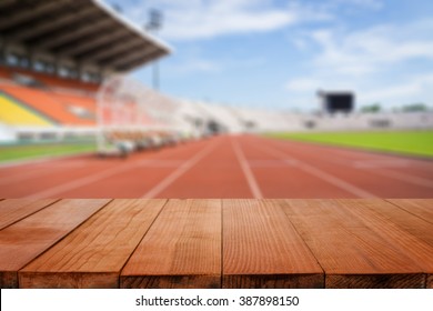 Wood Table Top On Blurred Background Of Red Running Tracks In Sport Stadium  - Can Be Used For Display Or Montage Your Products
