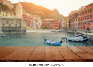 Wood Table Top On Blurred Background Of Manarola Village On Cliff Rocks And Sea At Sunset.Seascape In Five Lands, Cinque Terre ,Italy Europe.vintage Tone Color,can Be Used Display Your Products