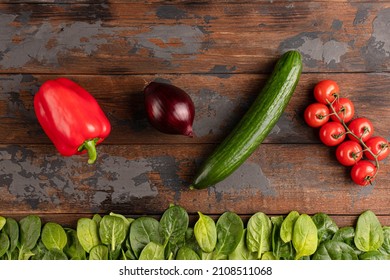 wood texture with vegetables, red pepper, cherry tomatoes, cucumber, spinach, red onion, top view