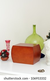 Wood Urn Filled With Loved Ones Ashes Surrounded By Memento Objects On A White Mantle.