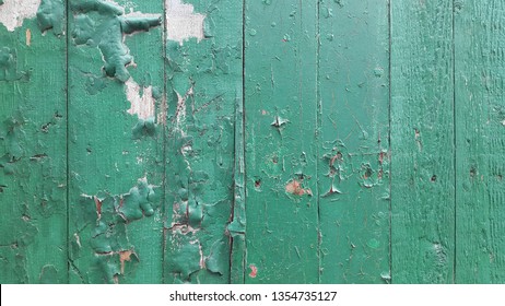 Wood. Vintage oldish background. Old painted wood with peeling paint. Wood painted surface. Panel of vertical boards. 
 Cracked layer of green paint