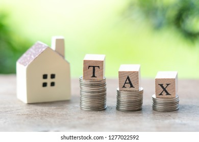 wood word TAX and model house with Clock stack of coins to thinking and planning. using as background Money, Financial, Business property real estate concept with copy space. - Shutterstock ID 1277022592