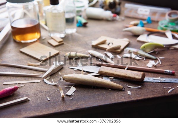Wood working. Wood carving. Making\
handcrafted fishing lures form balsa wood.Hand made fishing lures\
on a work table with tools in background. Shallow depth of field.\
Focus on foreground.