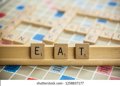 Woodbridge, New Jersey / United States - November 9, 2018: Scrabble Tiles Spell Out The Word Eat On A Vintage Game Board