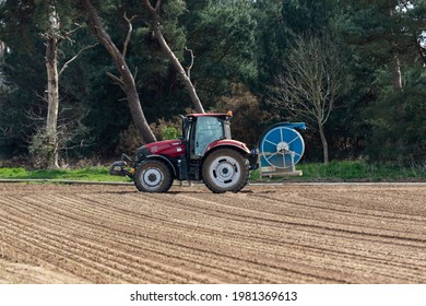 Woodbridge, Suffolk, UK April 24 2021: A tractor carrying irrigation equipment ready to lay down water pipes to water a farm field