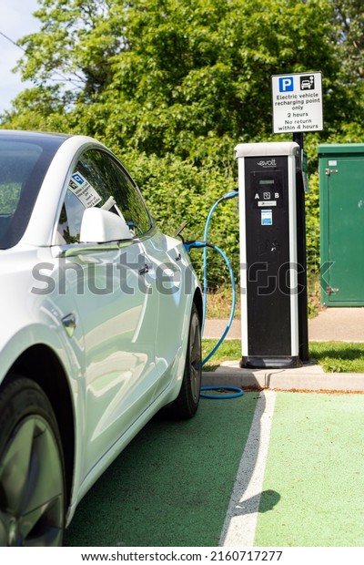Woodbridge Suffolk UK May 18 2022: A Tesla Model 3\
electric car charging at plug in charge station in a public car\
park in Suffolk, UK