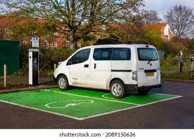 Woodbridge Suffolk UK November 28 2021: Nissan E-NV200 Electric Van Charging At Plug In Charge Station In A Public Car Park In Suffolk, UK