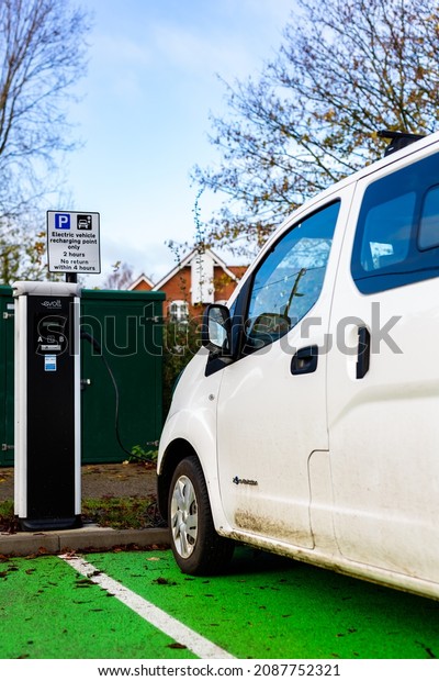 Woodbridge Suffolk UK November 28 2021: Nissan E-NV200\
electric van charging at plug in charge station in a public car\
park in Suffolk, UK
