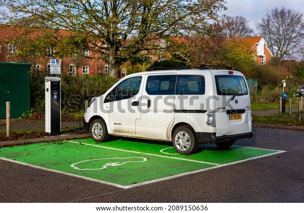 Woodbridge Suffolk UK November 28 2021: Nissan E-NV200\
electric van charging at plug in charge station in a public car\
park in Suffolk, UK