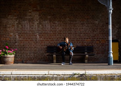 Woodbridge, Suffolk, UK September 13 2020: A 20 Something Female Relaxing And Playing An Acoustic Guitar Outside For Passers By To Listen Too