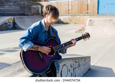 Woodbridge, Suffolk, UK September 13 2020: A 20 Something Female Relaxing And Playing An Acoustic Guitar Outside For Passers By To Listen Too