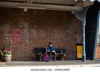 Woodbridge, Suffolk, UK September 13 2020: A 20 Something Female Relaxing And Playing An Acoustic Guitar Outside For Passers By To Listen Too