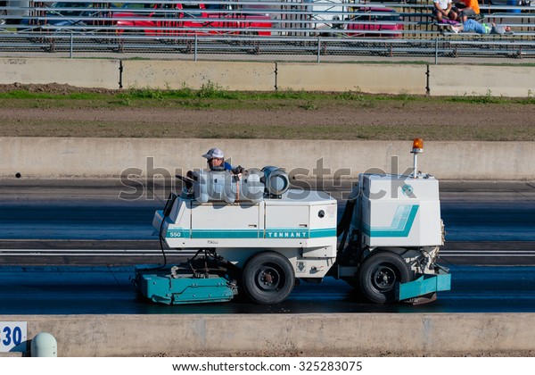 WOODBURN, OR - SEPTEMBER 27,\
2015: Worker on a track cleaning maching cleans the race surface\
after a crash at the NHRA 30th Annual Fall Classic at the Woodburn\
Dragstrip.
