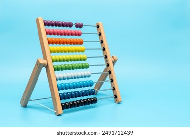 A wooden abacus with colorful beads on it. The beads are arranged in rows, and the abacus is placed on a blue background - Powered by Shutterstock