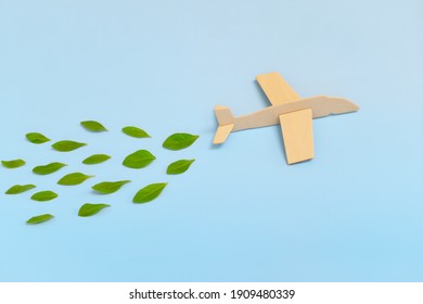 Wooden Airplane Model Emitting Fresh Green Leaves On Blue Background. Sustainable Travel; Clean And Green Energy; And Biofuel For Aviation Industry Concept.
