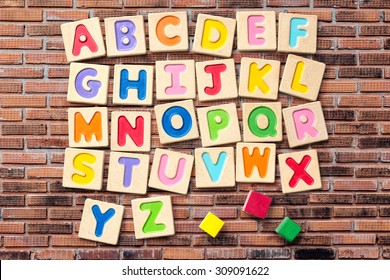 Wooden alphabet blocks with letters on brick wall 