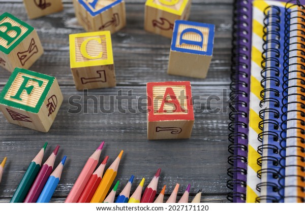 Wooden alphabet blocks on wooden background.
Back to school, games for kindergarten, preschool education.
pencils, notebooks, blocks on the
table.	
