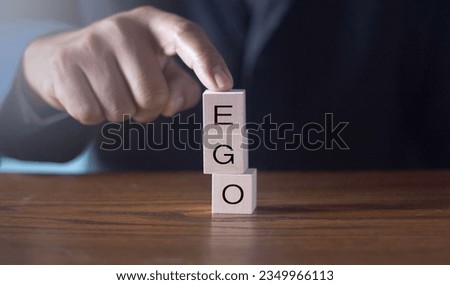 wooden alphabet blocks reading - Ego - balanced in the palm of his hand in a conceptual image.