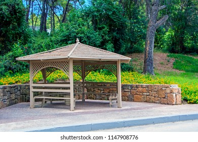 Wooden Arbor In Garden With Stone Low Wall On Background